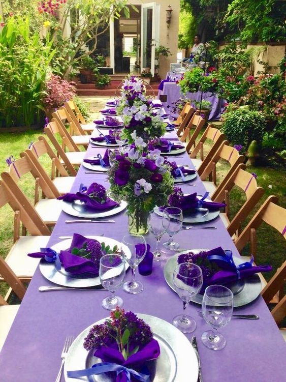 the table is set with purple and white place settings