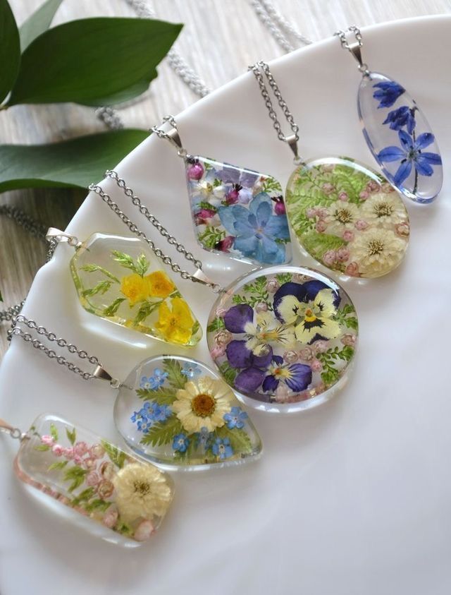 six glass pendants with flowers on them sitting on a plate next to a plant