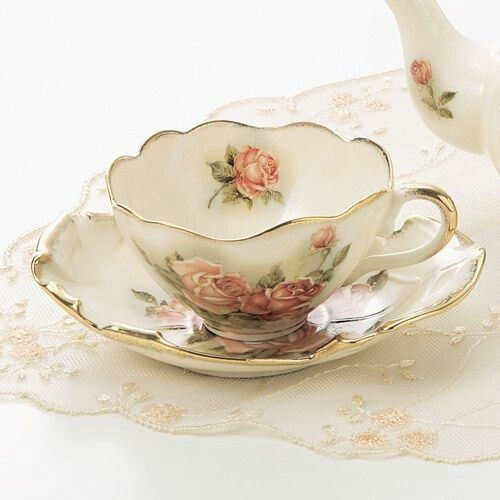 a tea cup and saucer on a lace tablecloth