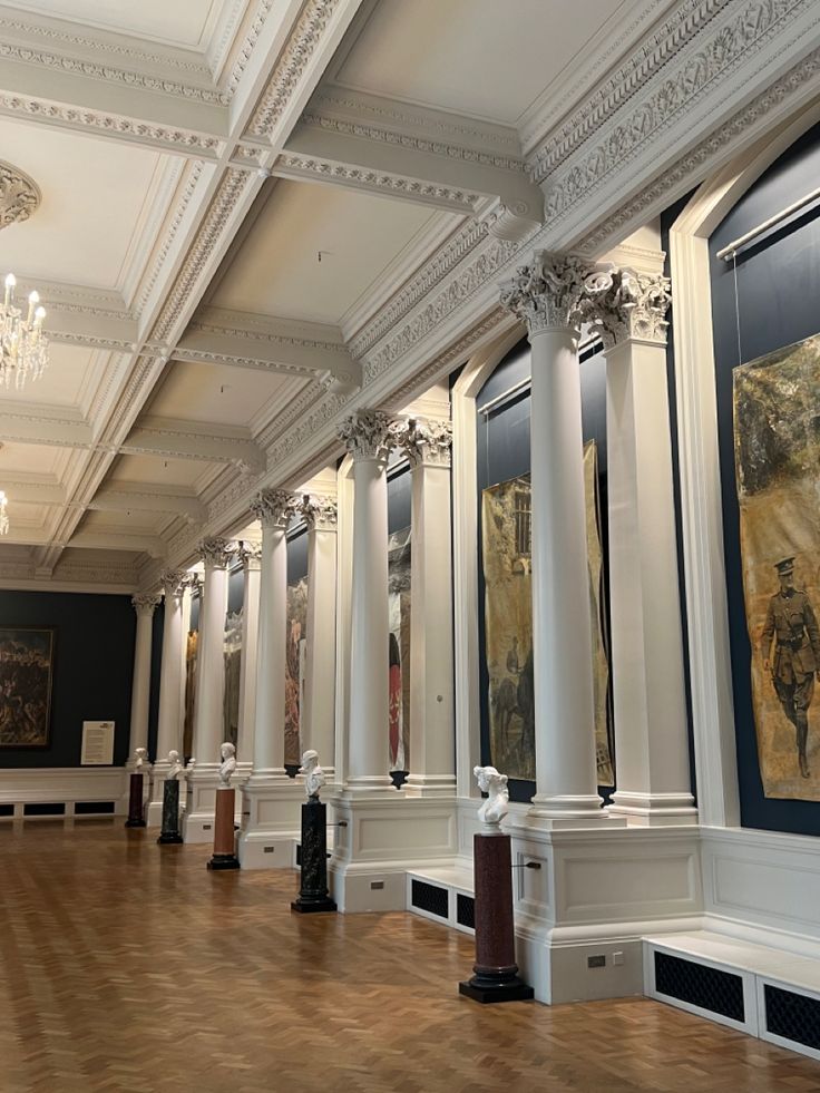 an empty room with columns and paintings on the walls