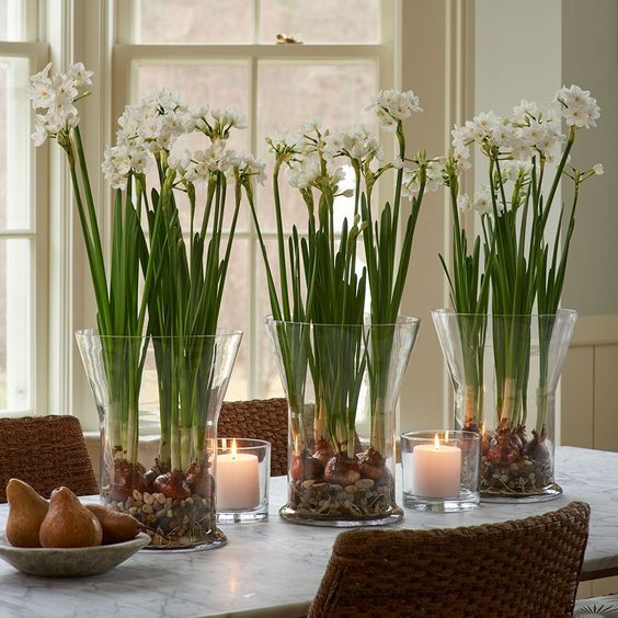 vases filled with flowers sitting on top of a table next to fruit and candles