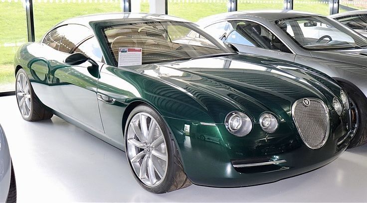 two green cars are parked next to each other in front of a large window with grass behind them