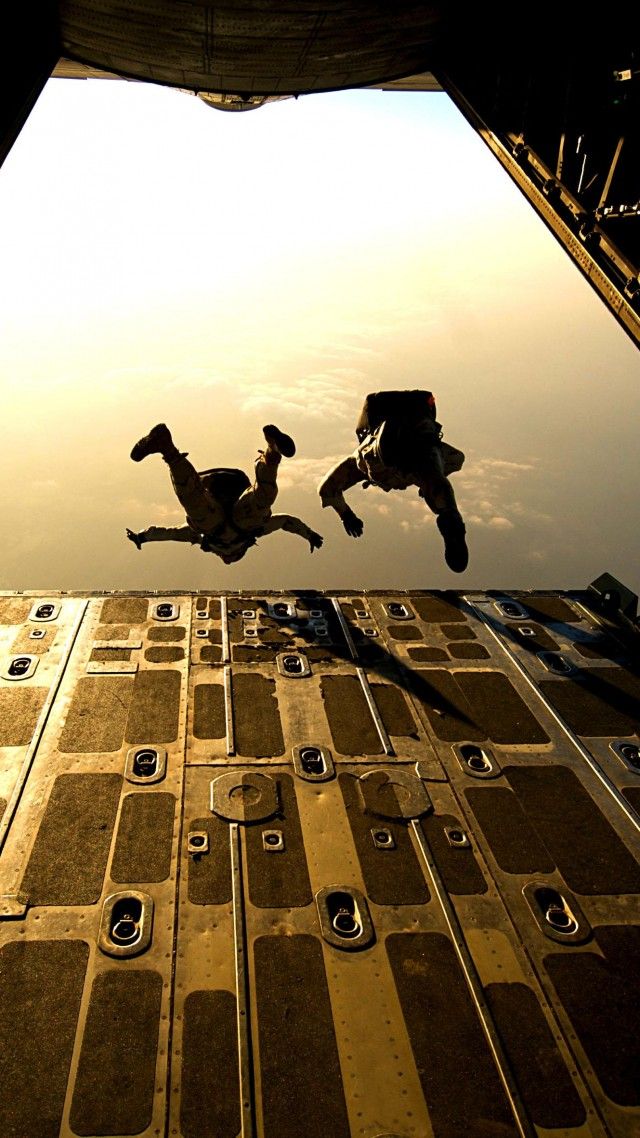 two people jumping off the side of a building into the air with their feet in the air