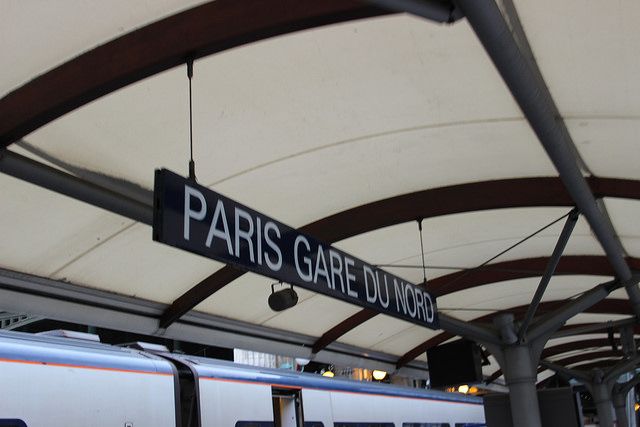 a sign that is hanging from the side of a train station roof in paris, france