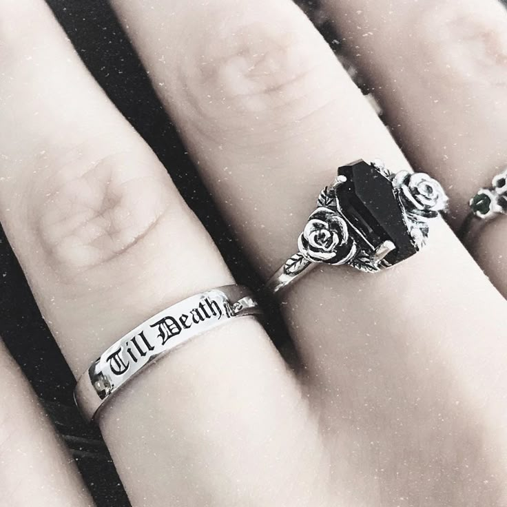 three different rings on someone's hand with their names engraved on the ring finger