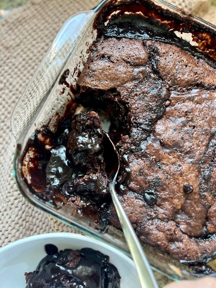 a close up of a cake in a pan on a table with a spoon and bowl