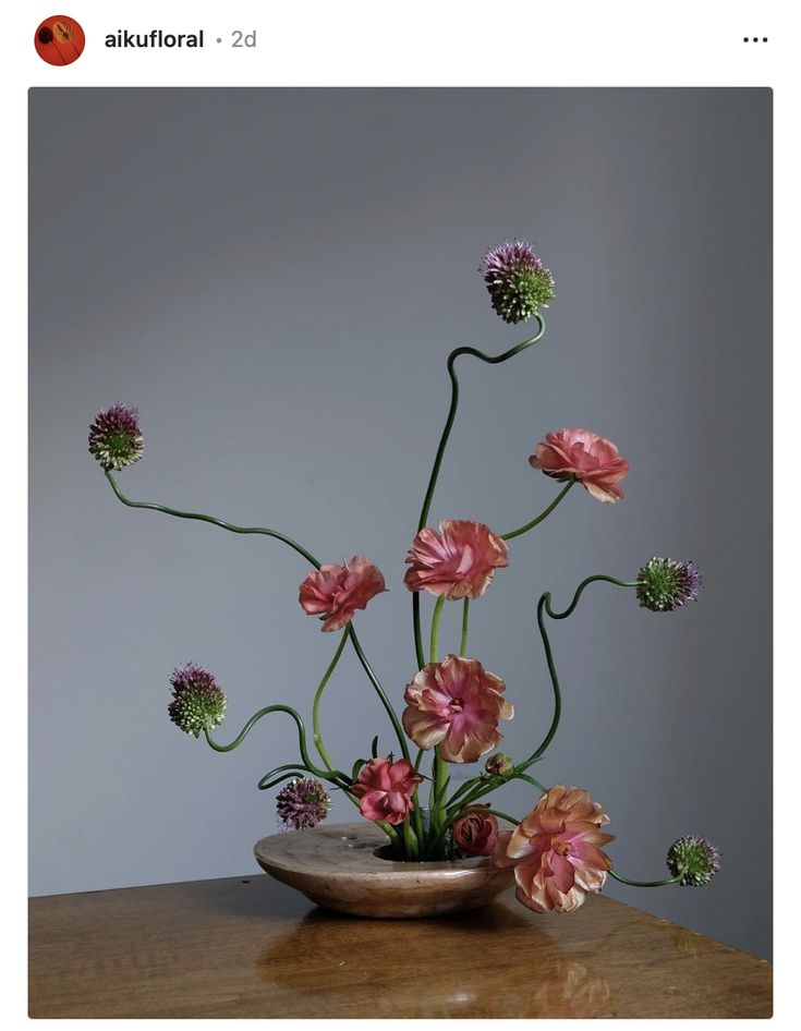 a vase filled with pink flowers on top of a wooden table