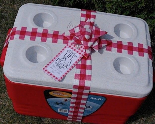 a red and white picnic cooler wrapped in paper with a bow tied around the top