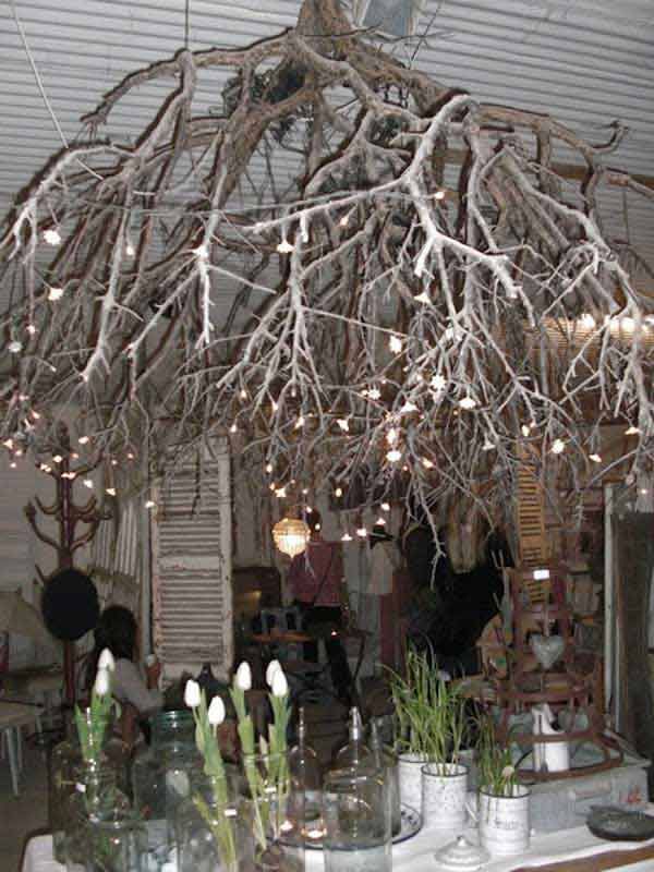 a dining room table with vases and branches hanging from the ceiling