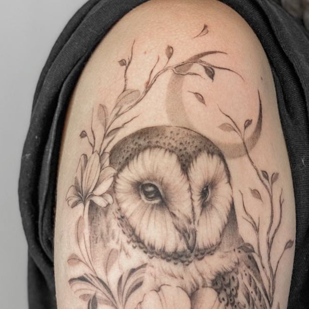 an owl tattoo on the arm with flowers