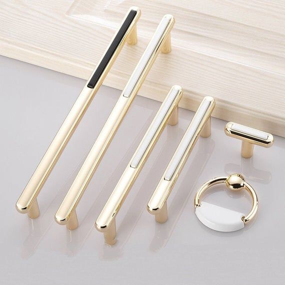 four different types of metal door handles on a white surface next to a pair of rings