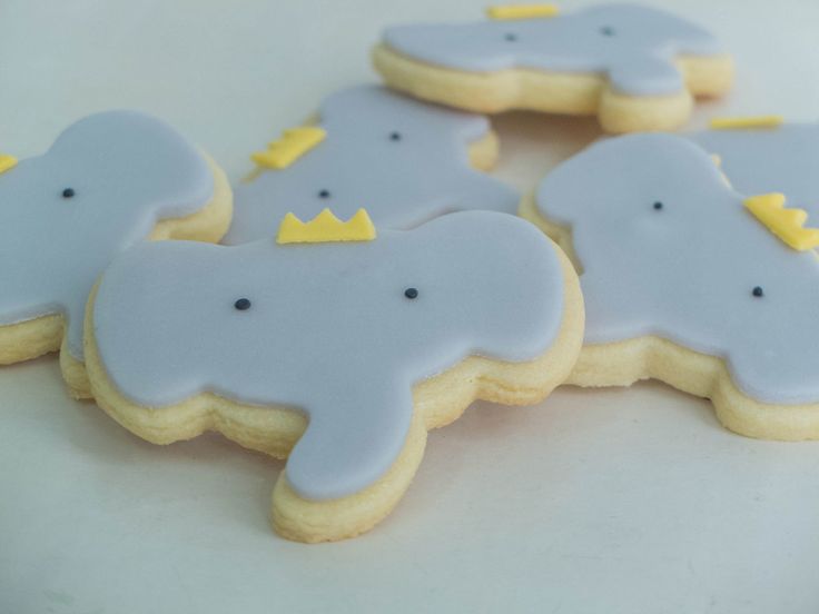 some decorated cookies are sitting on a white tablecloth with yellow and blue icing