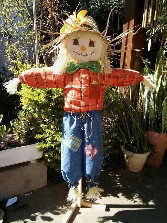 a scarecrow is standing in front of some plants