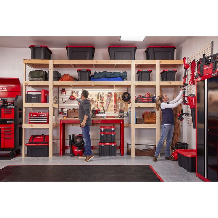 two men working in a garage with tools on the wall and shelves full of toolboxes