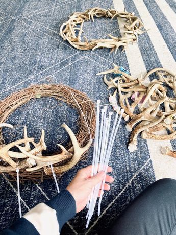 a person sitting on the floor next to a wreath and antlers with sticks sticking out of it