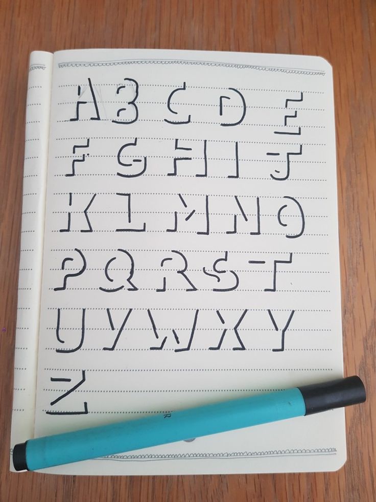 a pen sitting on top of an open notebook next to a cursive alphabet