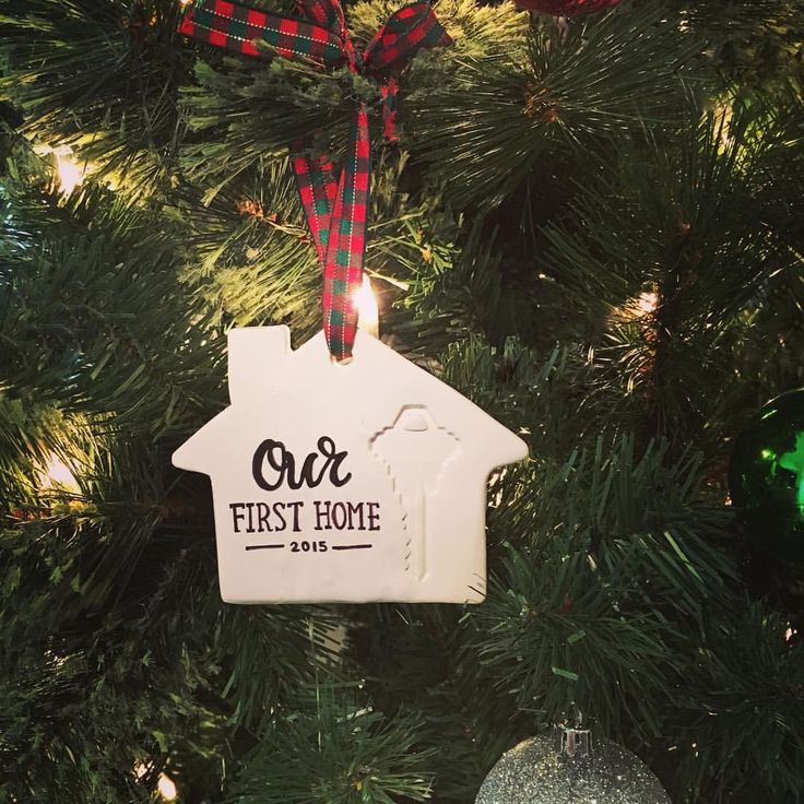 a christmas ornament hanging from a tree with ornaments around it and the words our first home