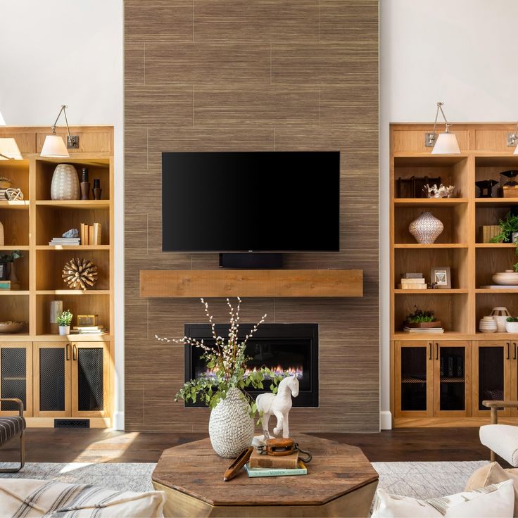 a living room filled with furniture and a flat screen tv mounted on a wall above a fire place