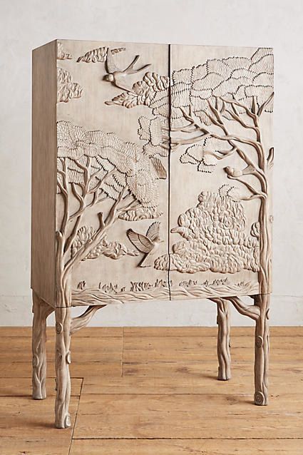 an intricately carved cabinet with birds and trees on the doors is sitting on a wooden floor