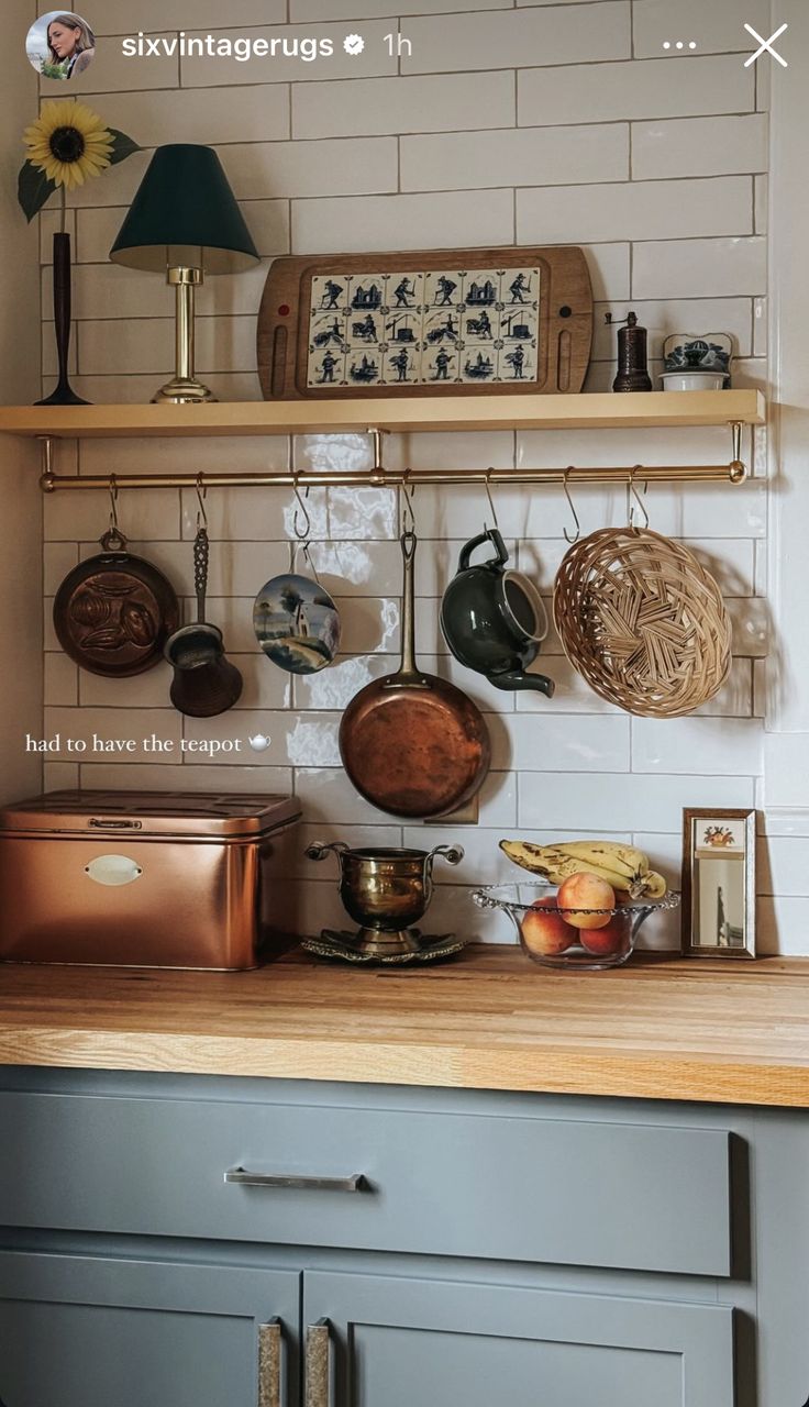 pots and pans are hanging on the wall above the kitchen counter, along with other cooking utensils