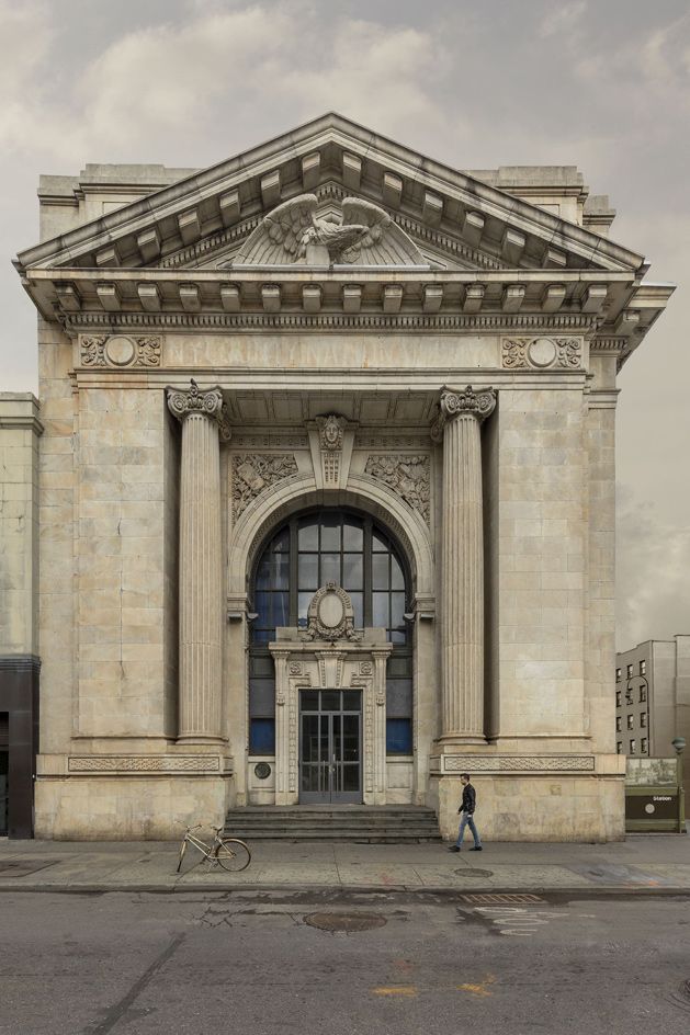 an old building with a man walking in front of it and a bicycle leaning against the door