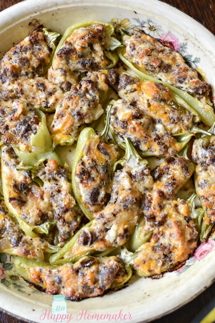 an oval casserole dish filled with stuffed bell peppers and sausages, ready to be eaten