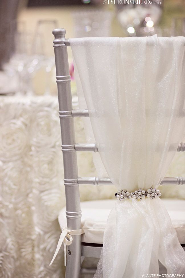 an image of a chair that is decorated with white fabric and pearls on the back