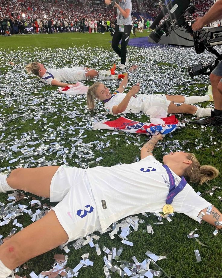 two female soccer players laying on the ground with confetti