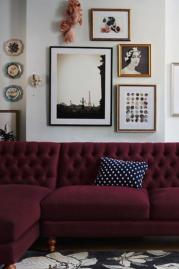 a red couch sitting in front of pictures on the wall