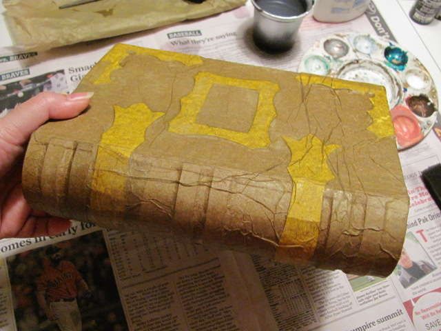 a person is holding a piece of cardboard with yellow paint on it and some other crafting supplies