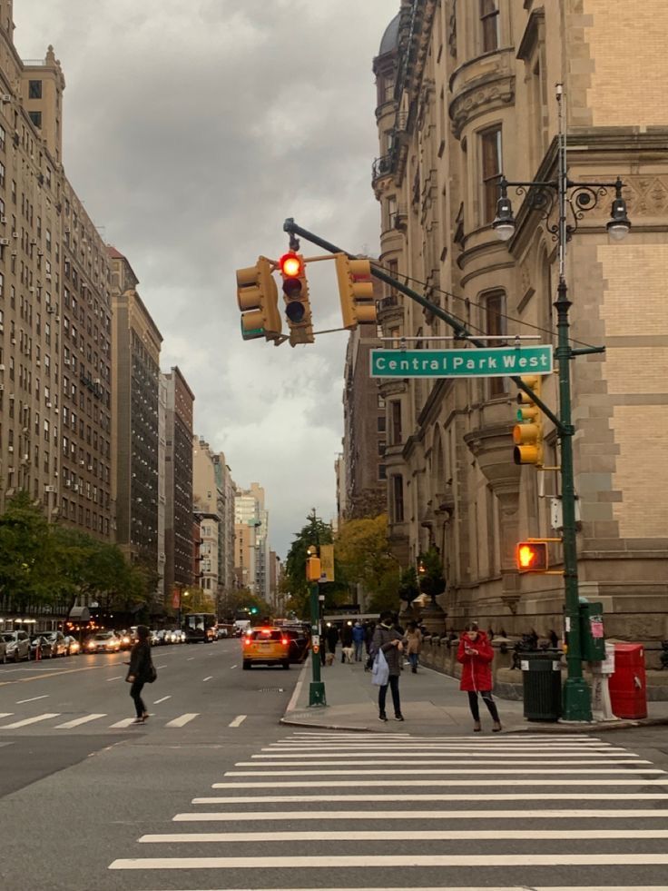 people crossing the street at an intersection in new york city, with traffic lights and tall buildings