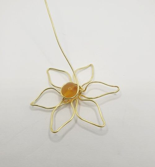 a gold plated necklace with a flower shaped pendant hanging from it's side