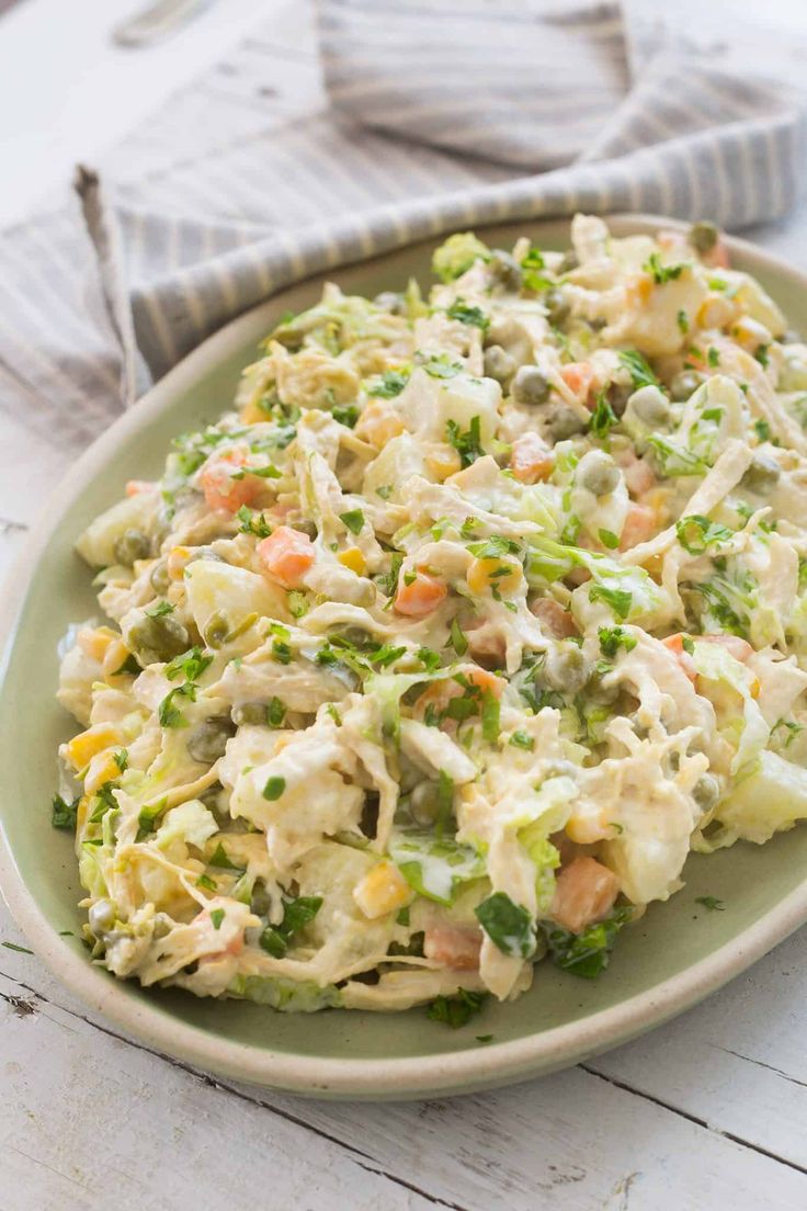 a green plate topped with coleslaw and carrots on top of a wooden table