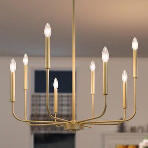 a gold chandelier with six candles hanging from the ceiling in a living room