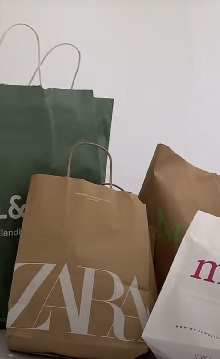 three shopping bags sitting next to each other on top of a counter with the word zara printed on them