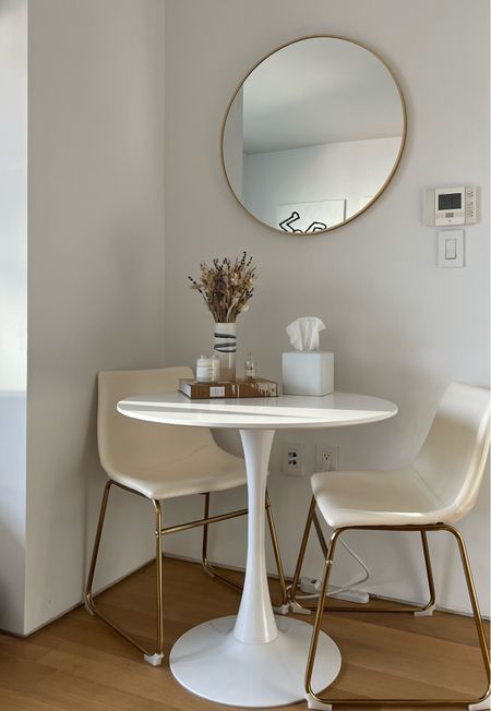 a white table with two chairs and a round mirror