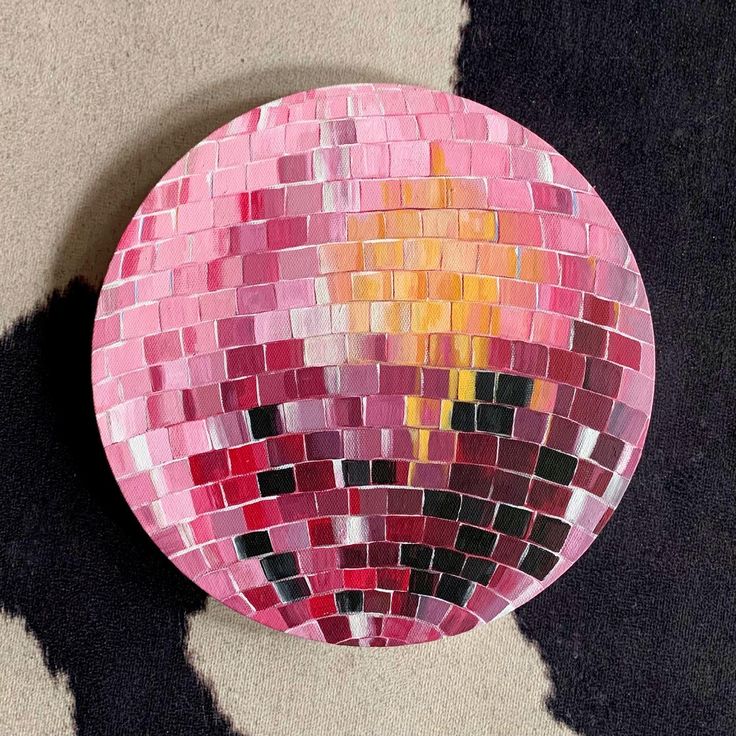 a pink and yellow mosaic tile plate sitting on the floor