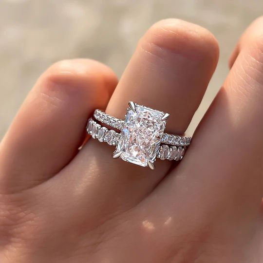 a woman's hand with a diamond ring on top of her finger and an engagement band