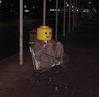 a person sitting in a shopping cart with a smiley face on it's head