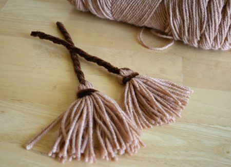 two tassels are sitting on the floor next to a piece of string and yarn