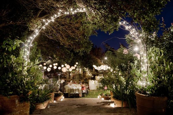 an outdoor dining area is lit up with fairy lights