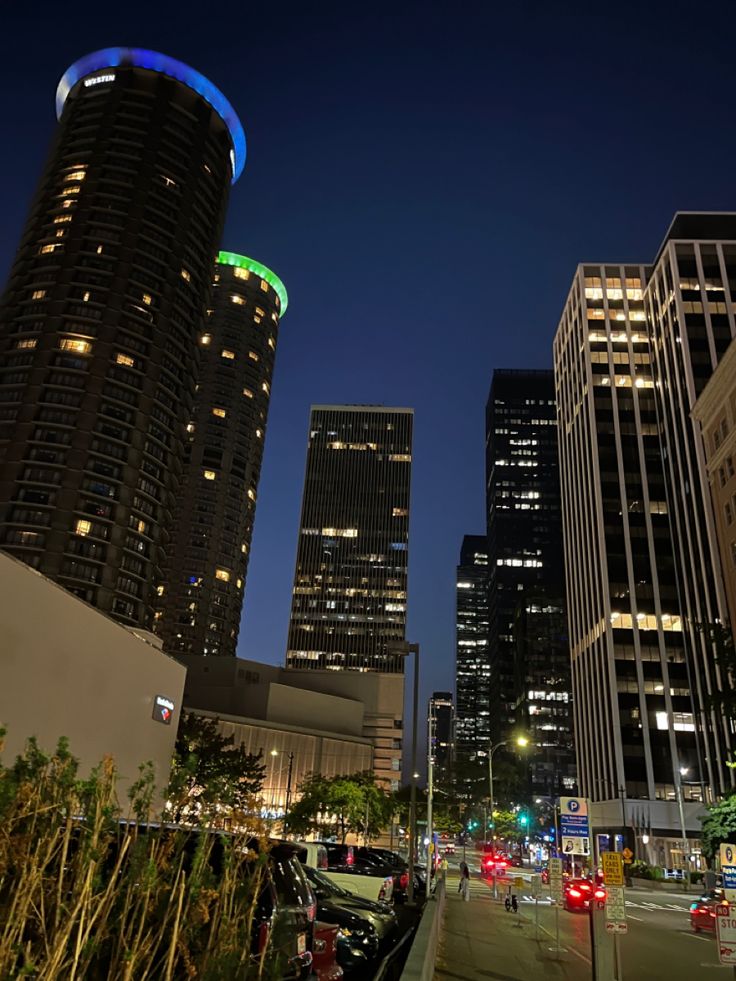 the city skyline is lit up at night with tall buildings and skyscrapers in the background