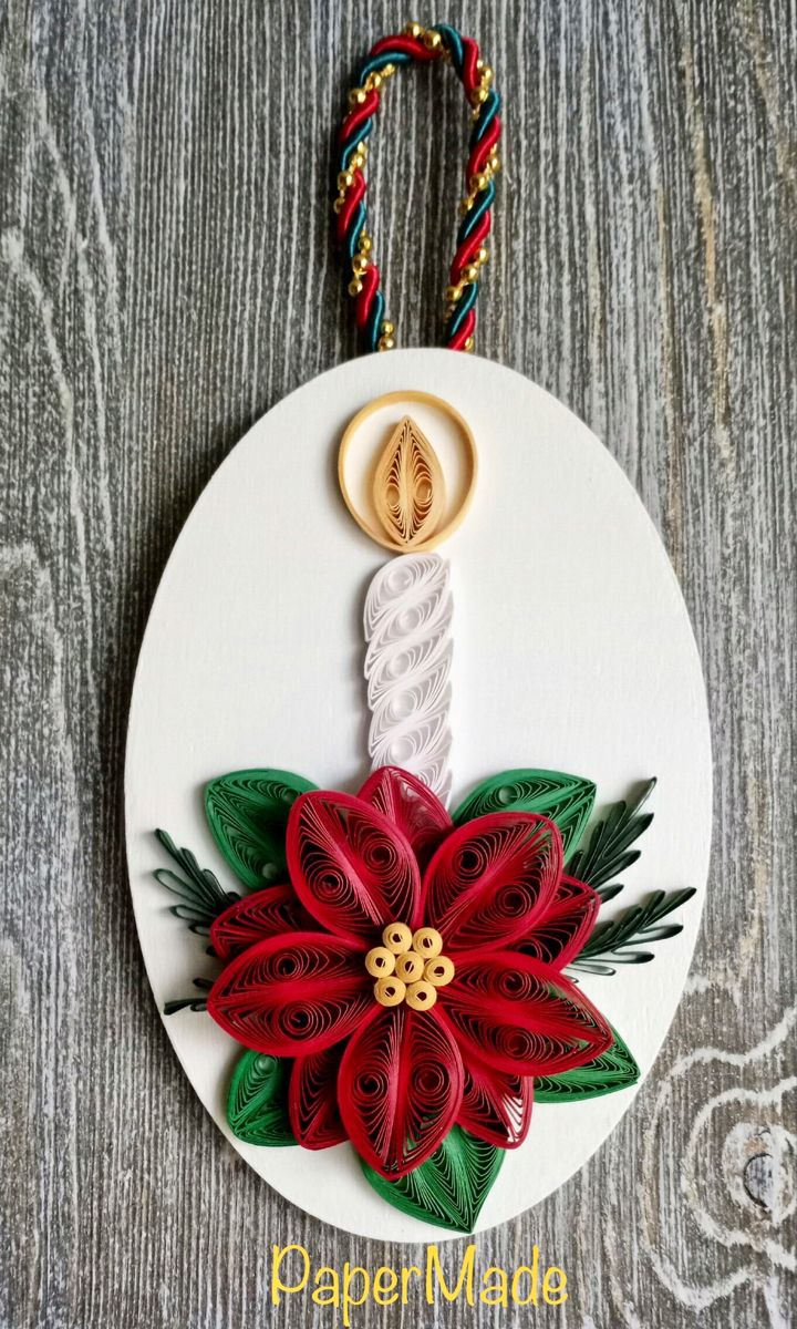 a white ornament with red and green poinsettia on it's side