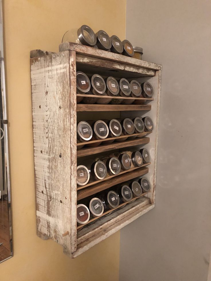 an old wooden box with cans on it hanging from the wall next to a mirror