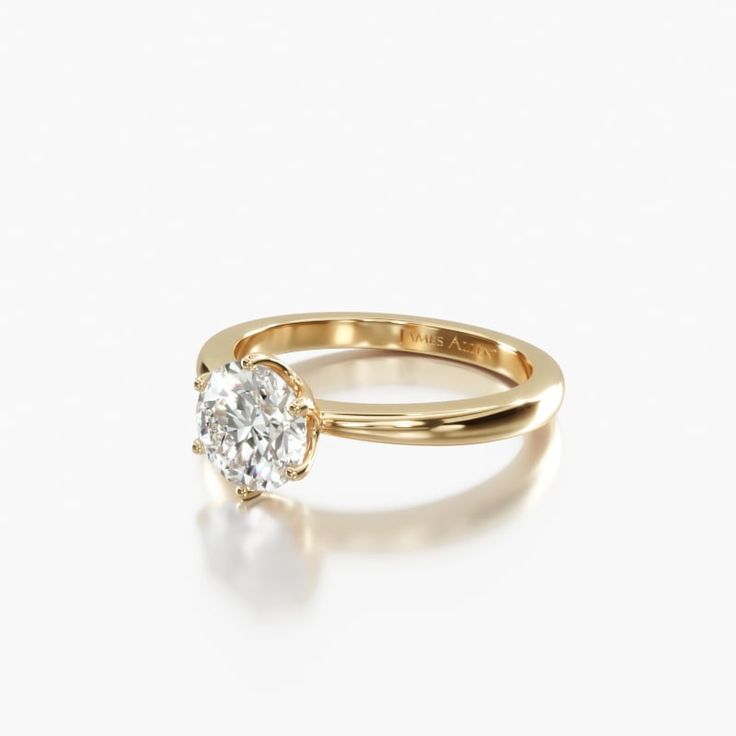 a yellow gold engagement ring with a single diamond in the center, on a white background