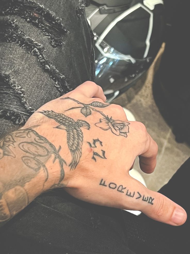 a person with a tattoo on their arm holding his hand up to the camera while sitting in front of a motorcycle