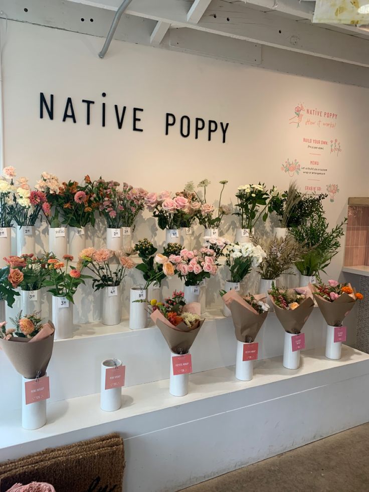 many flowers are in vases on display at the flower shop's front counter