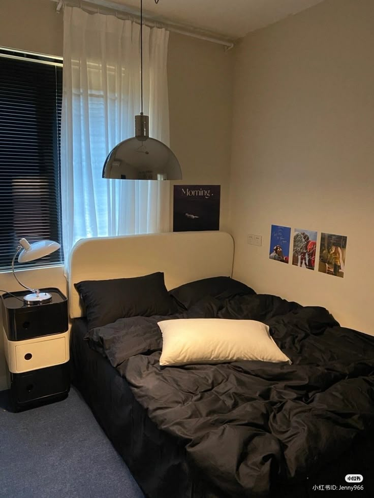 an unmade bed with black sheets and white pillows next to a window in a bedroom