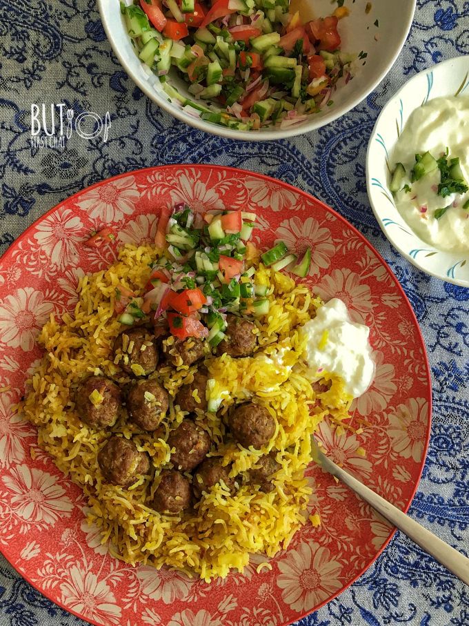 a plate with meatballs and rice next to two bowls of vegetables on a table