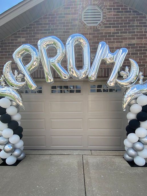 an arch made out of balloons with the word prom written on it